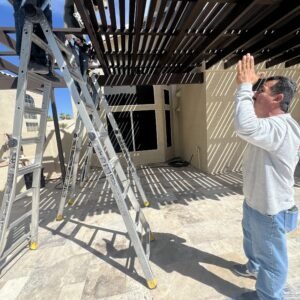 Phoenix Rain Gutters Arizona working on top of a ladder and installing a alumawood patio cover.