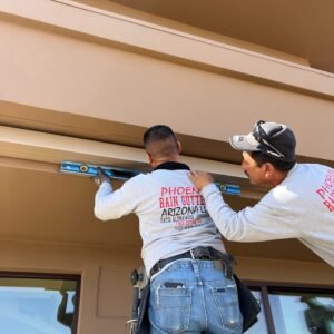 Phoenix Rain Gutters Arizona working on top of a ladder leveling a rain gutter.