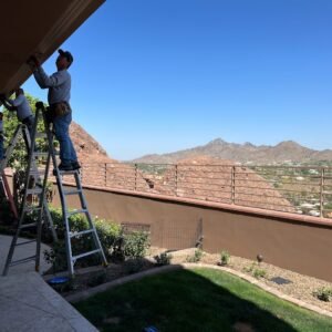 Phoenix Rain Gutters Arizona working on top of a ladder leveling a rain gutter.