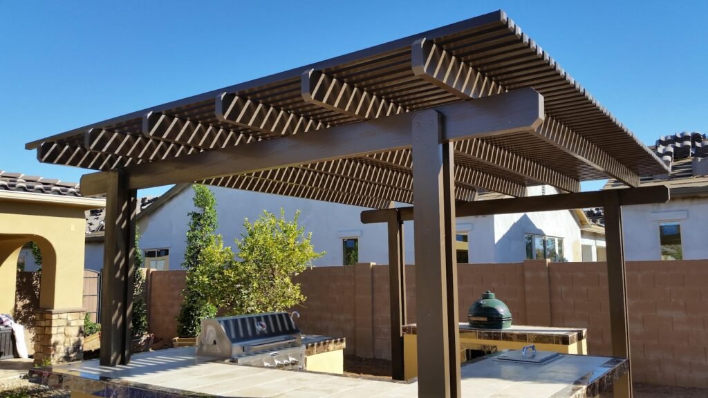 A midsize patio cover shading a backyard barbeque. The patio is dark brown and lattice style.