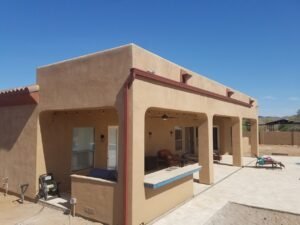 Back of a sante fe house with three scupper boxes and one seamless k-style aluminum rain gutter running along to the side of the house with one downspout.