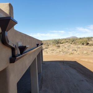 A Sante Fe house with Scupper Boxes and Rain Gutters. In the background there is a view of the arizona desert.