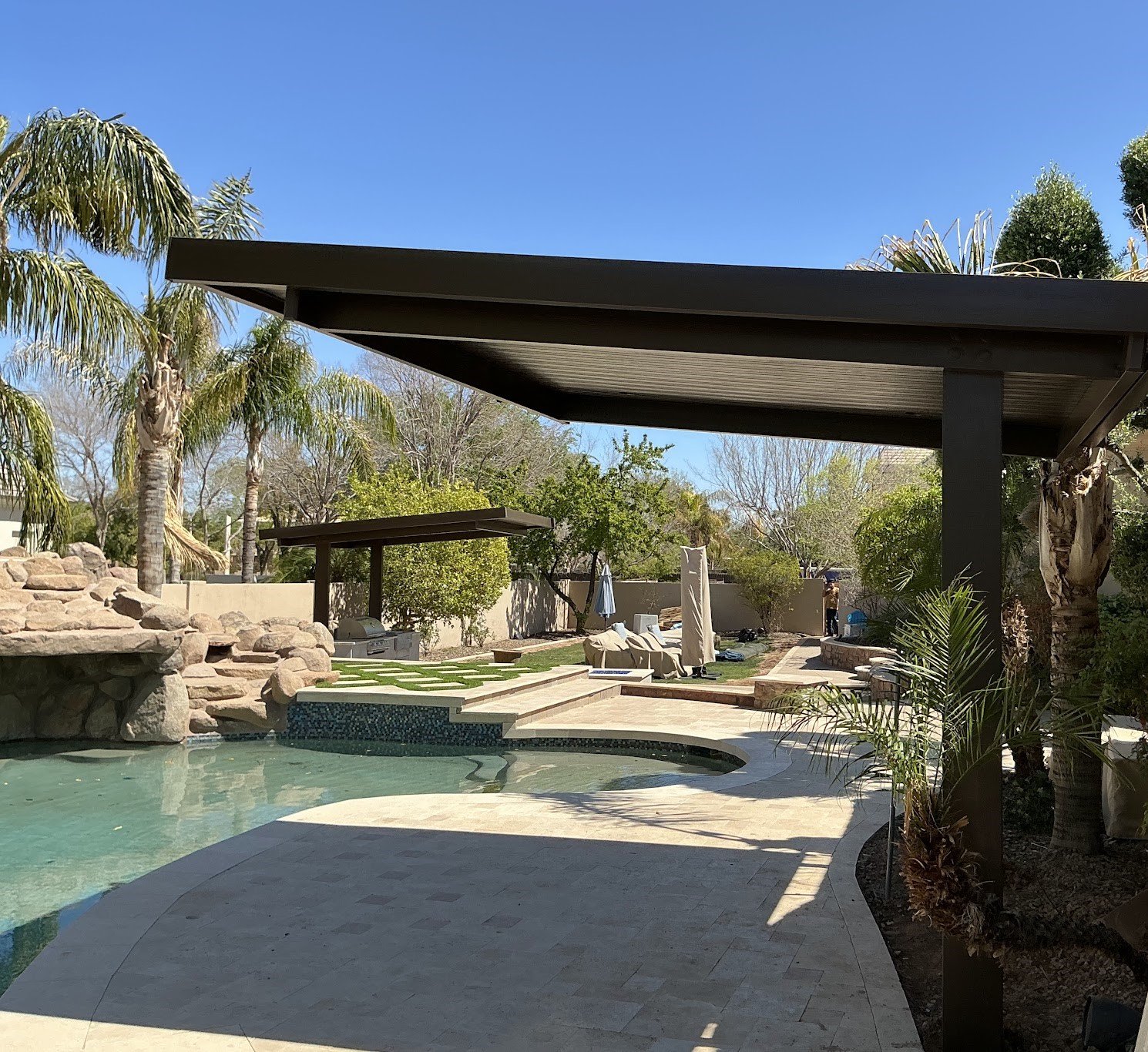 Aluminum cantilever patio cover with a solid roof installed beside a backyard pool in Phoenix, Arizona
