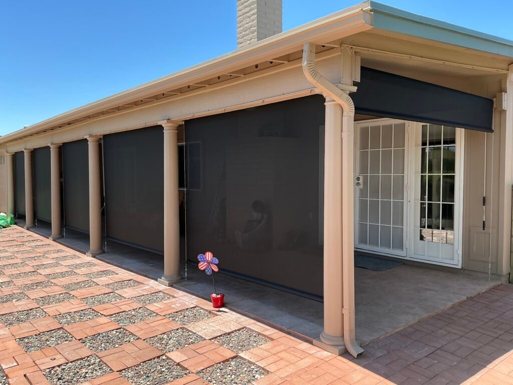 Six custom black roll-down shades installed between the columns of a covered patio in Phoenix