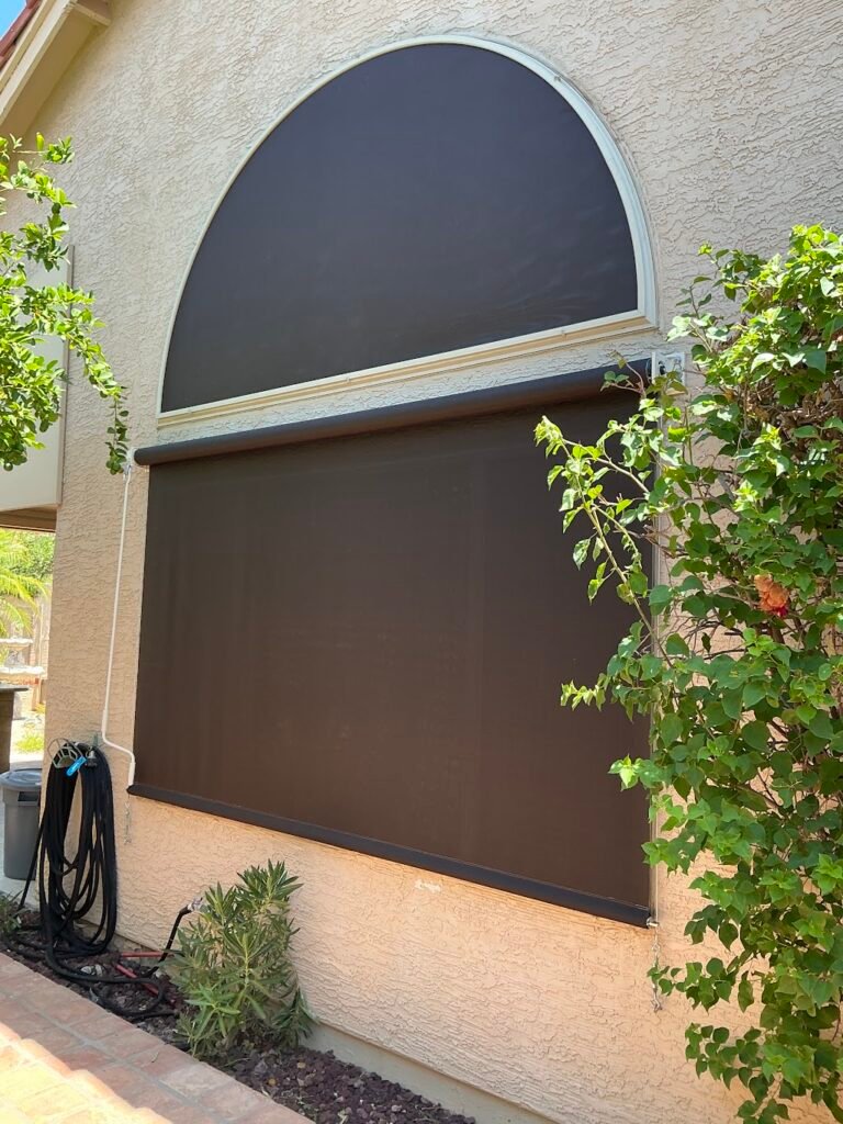 Custom arched sun screen and manual roll-down shade installed on two exterior windows of a Phoenix-area home